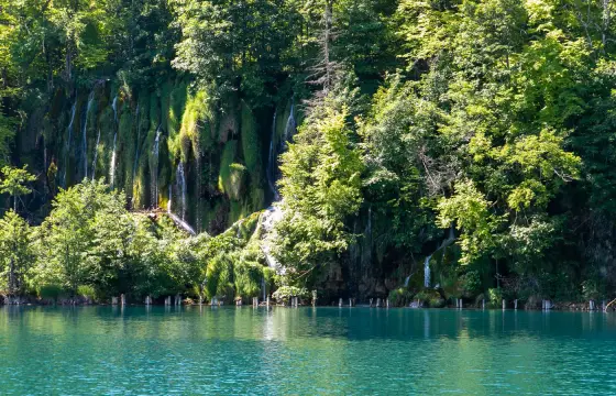 Ein türkiser See in Plitvice mit Wasserfällen am Ufer