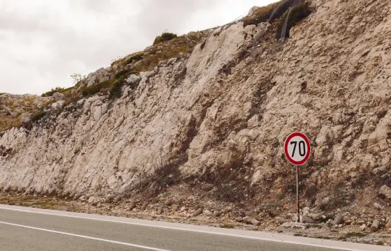 Ein Tempolimit-Schild an einer leeren Straße im Kalkfelsen
